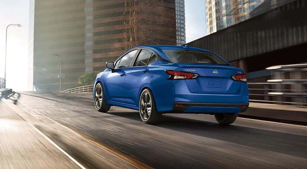 A blue 2024 Nissan Versa SR is shown driving on a city street.
