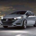 A silver 2024 Nissan Versa SR is shown driving near a city.