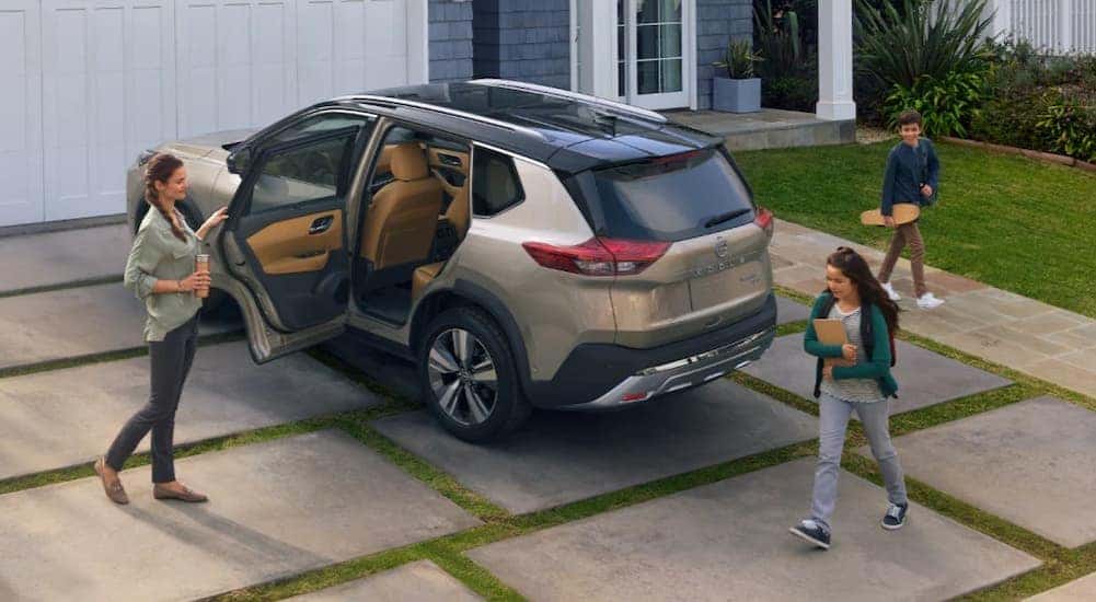 A tan 2024 Nissan Rogue Platinum is shown parked on a driveway.