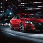 A red 2023 Nissan Altima SR is shown driving on a city street to view a used Nissan Altima for sale.