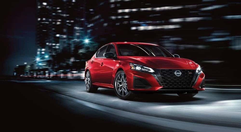 A red 2023 Nissan Altima SR is shown driving on a city street to view a used Nissan Altima for sale.