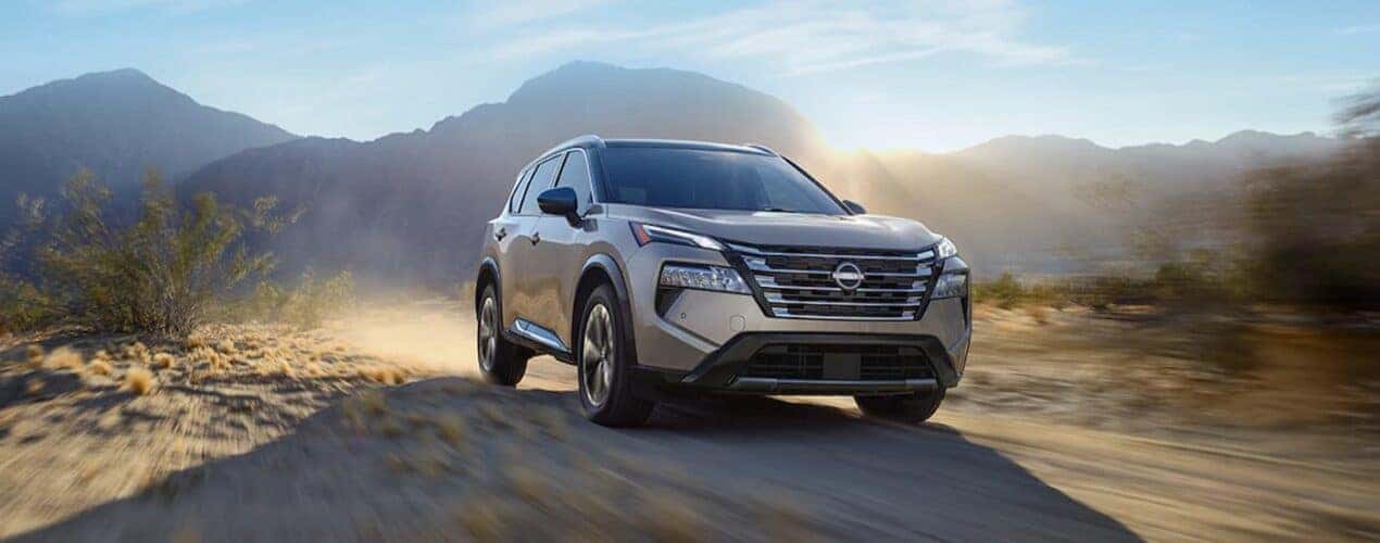 A silver 2024 Nissan Rogue is shown driving off-road.