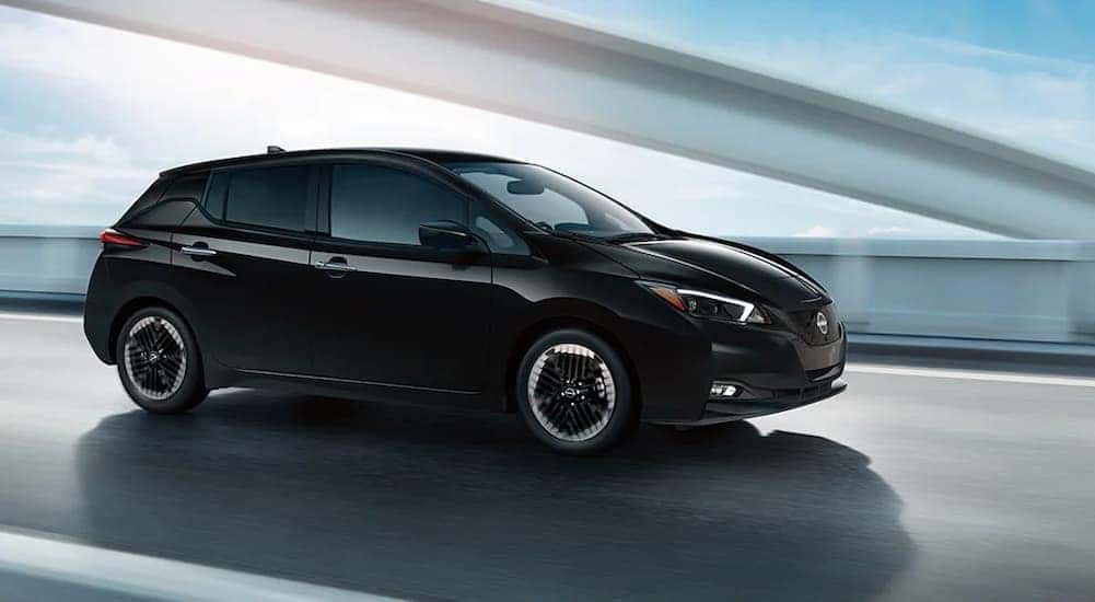 A black 2025 Nissan Leaf SV Plus is shown driving on a bridge.