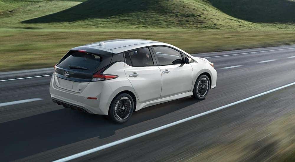 A white 2025 Nissan Leaf SV Plus is shown driving on a highway.
