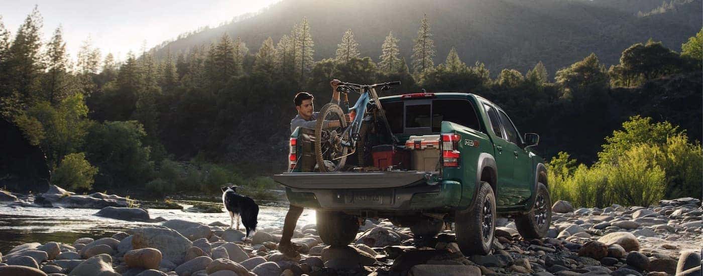 A green 2023 Nissan Frontier Pro-4x is shown from the rear after leaving a dealer that has used cars for sale.