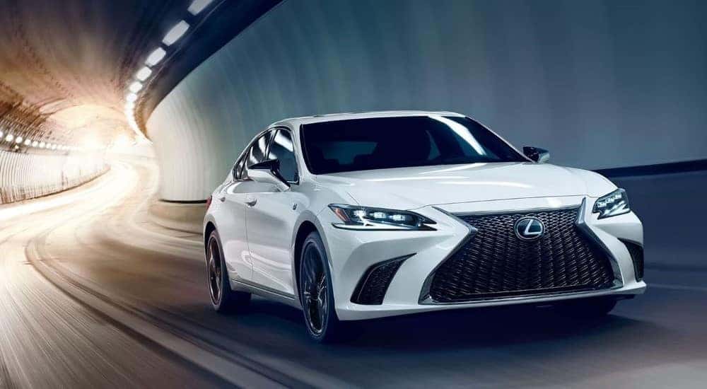 A white 2023 Lexus ES driving through a tunnel to a dealer with used cars for sale.