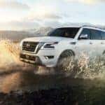 A white 2023 Nissan Armada splashing through water while off-roading.