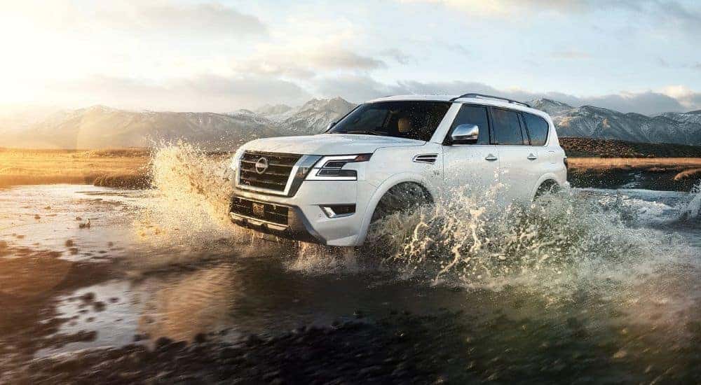 A white 2023 Nissan Armada splashing through water while off-roading.