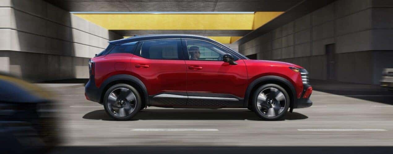 A red 2025 Nissan Kicks SR is shown driving on a city street.