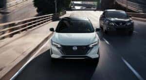 Head-on view of a white 2024 Nissan Sentra SR driving to a Nissan dealer.