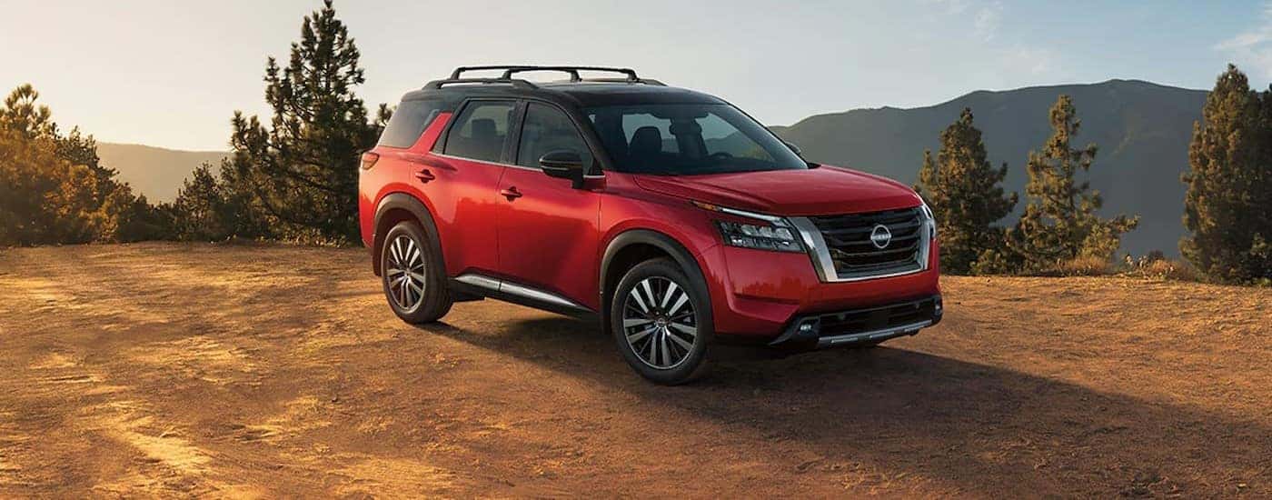A red 2024 Nissan Pathfinder is shown parked off-road.
