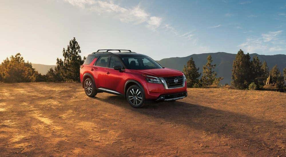 Right angled view of a red 2025 Nissan Pathfinder parked off-road.