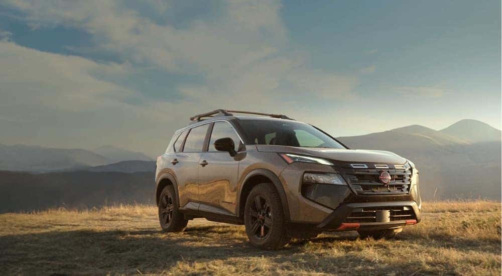A tan 2025 Nissan Rogue Rock Creek parked on a grassy hill after visiting a Nissan dealer near Monticello.