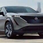 A gray 2025 Nissan ARIYA is shown driving near a city.