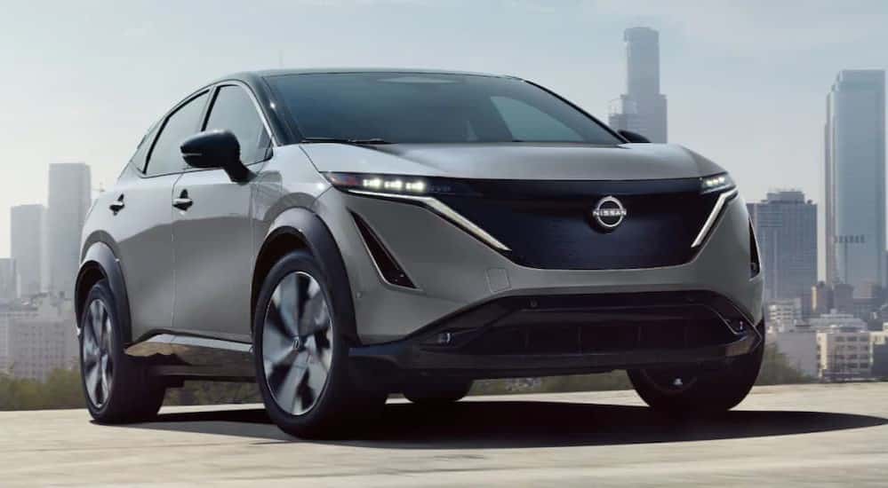 A gray 2025 Nissan ARIYA is shown driving near a city.