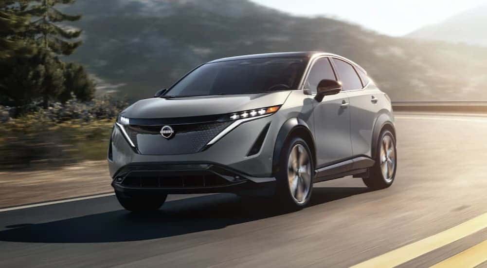 A gray 2025 Nissan ARIYA is shown driving on a highway.