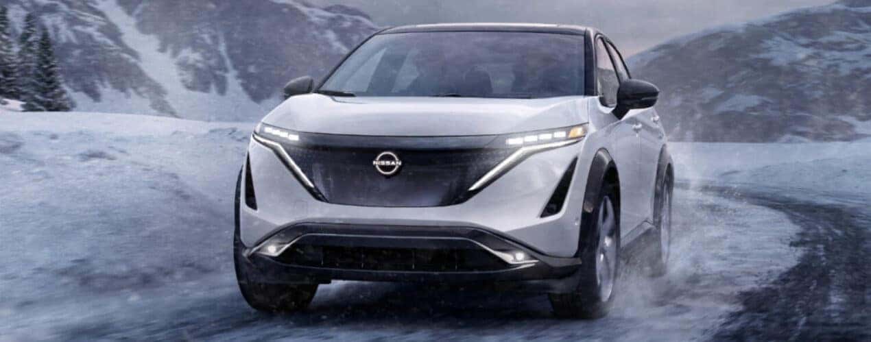 A white 2025 Nissan ARIYA is shown rounding a snowy corner.