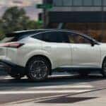 A white 2025 Nissan Murano Platinum is shown driving on a city street.