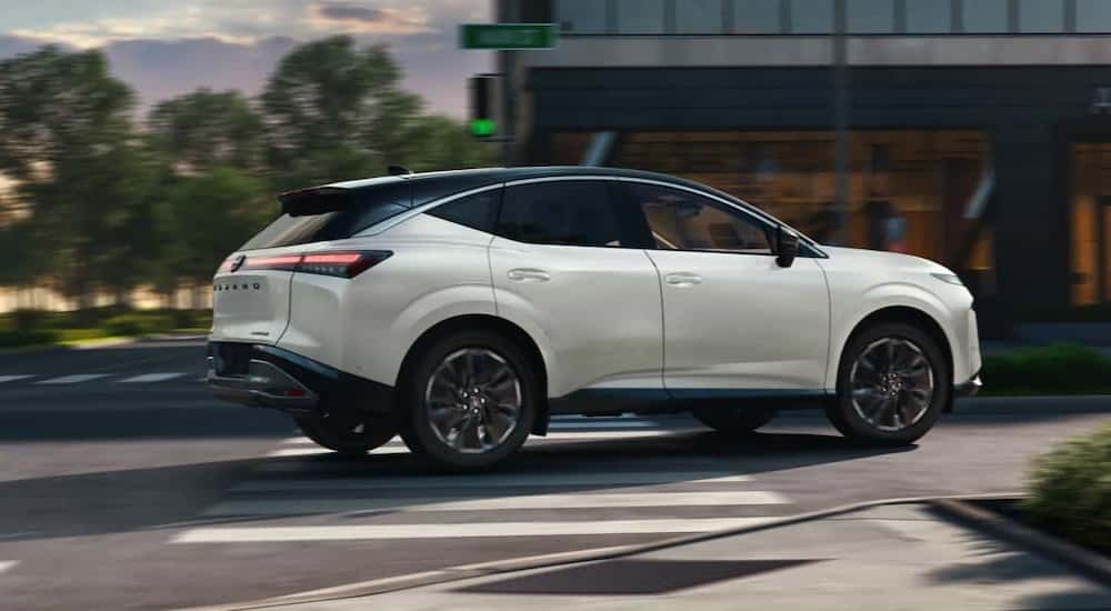 A white 2025 Nissan Murano Platinum is shown driving on a city street.