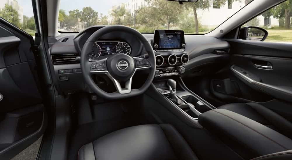 The black interior of a 2025 Nissan Sentra is shown from the driver's side.