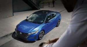 A blue 2024 Nissan Sentra for sale in Champaign is shown parked on pavement.