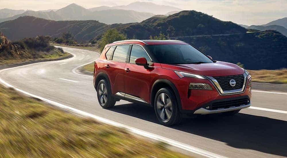 A red 2025 Nissan Rogue driving on a highway.