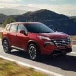 A red 2025 Nissan Rogue driving on a highway.