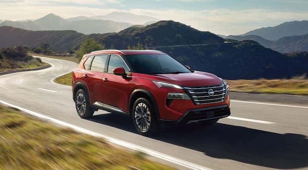 A red 2025 Nissan Rogue driving on a highway.