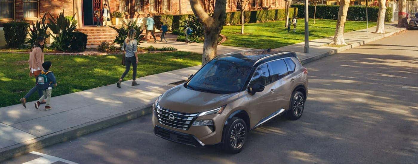 Brown 2025 Nissan Rogue parked on the side of a street.