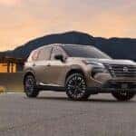 A tan 2025 Nissan Rogue parked near a house.