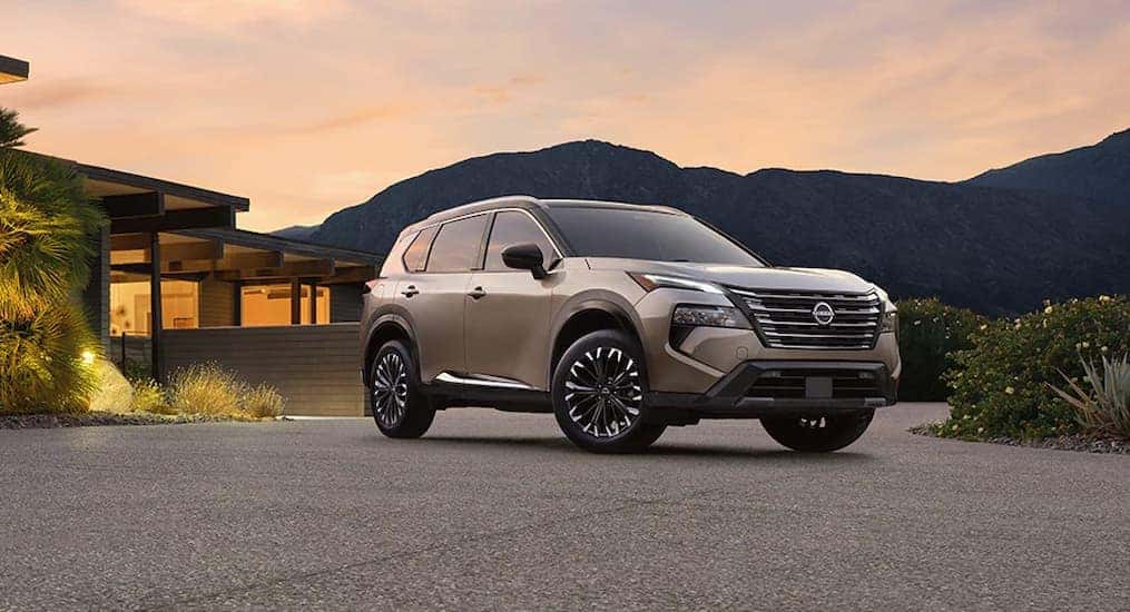 A tan 2025 Nissan Rogue parked near a house.