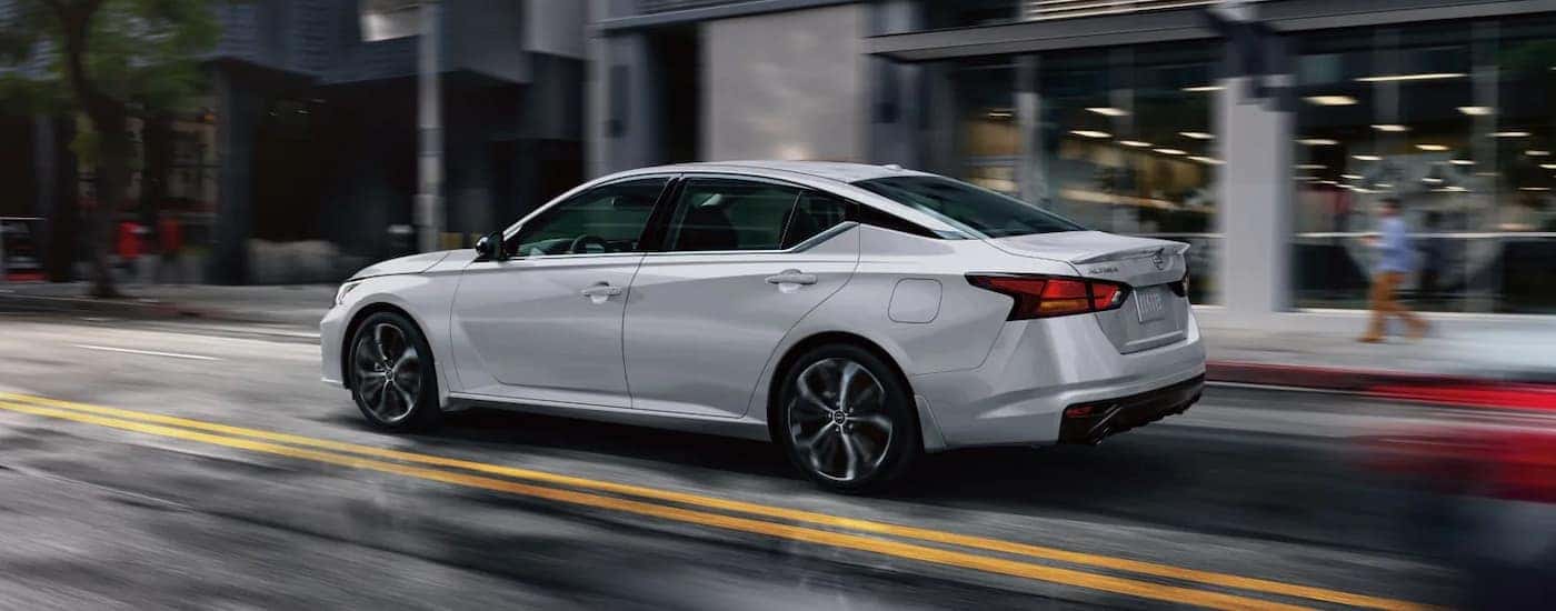 A silver 2025 Nissan Altima driving down a city street