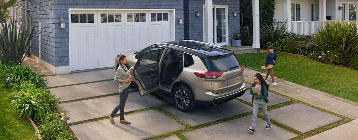 A tan 2025 Nissan Rogue in a driveway with a family getting inside