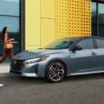A blue 2025 Nissan Sentra SR parked near two people walking.