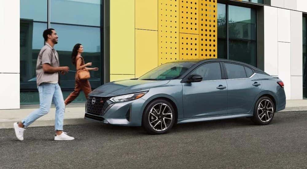 A blue 2025 Nissan Sentra SR parked near two people walking.