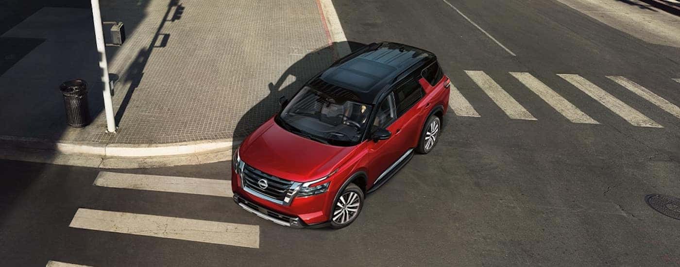 A red 2025 Nissan Pathfinder from the front while rounding a bend.