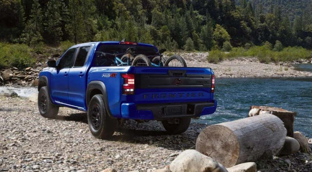 A blue 2025 Nissan Frontier parked off-road near a lake