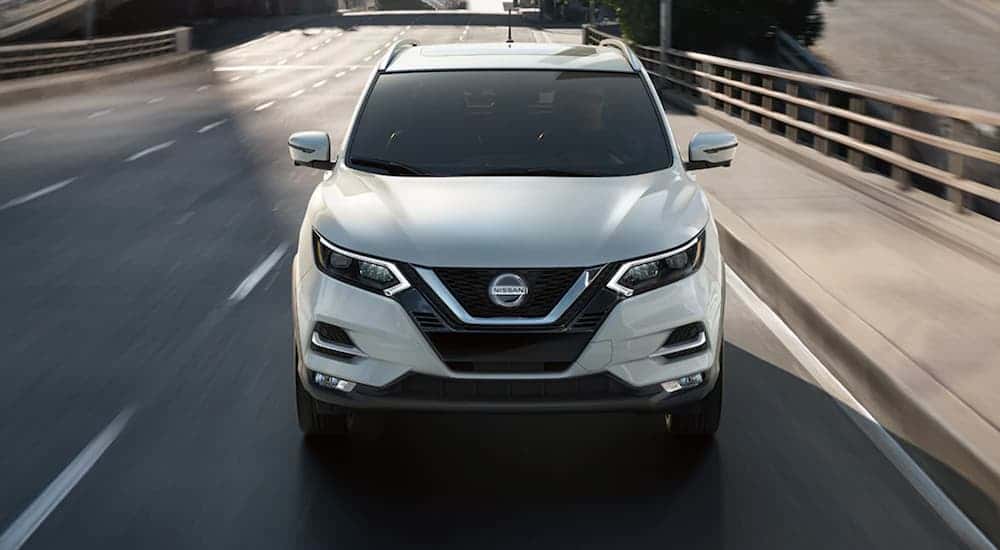 A white used 2021 Nissan Rogue Sport driving down a street