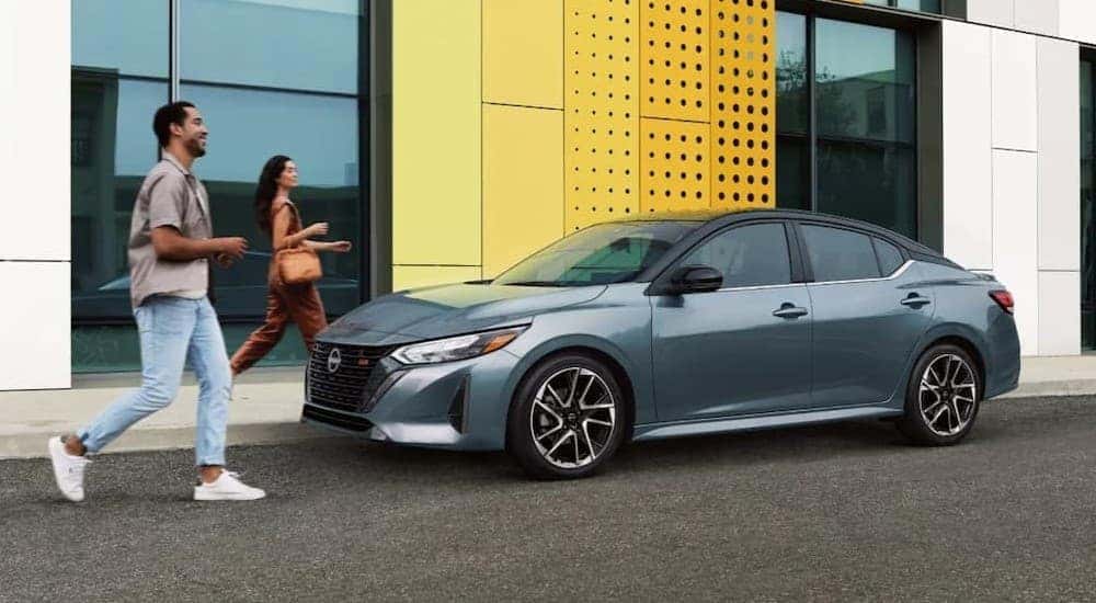 Two people walking to a blue 2025 Nissan Sentra.