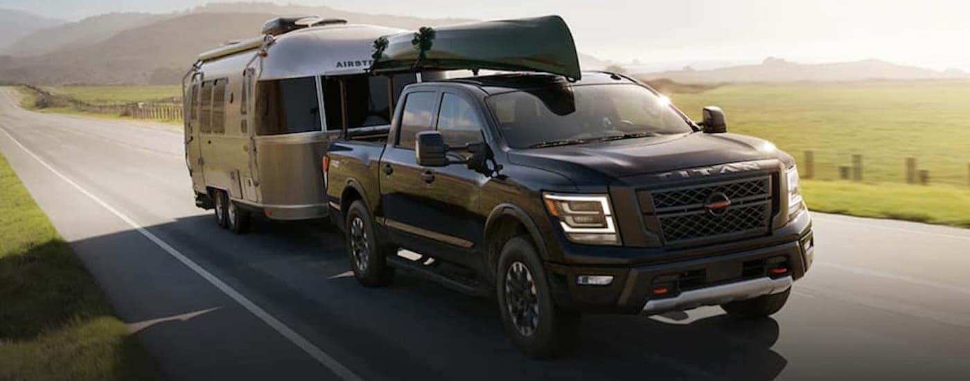 A black used 2021 Nissan Titan PRO 4X towing an Airstream camper