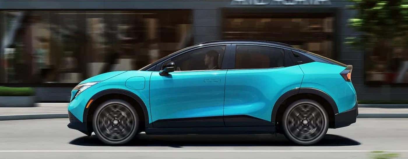 An aqua 2026 Nissan LEAF driving in a city.