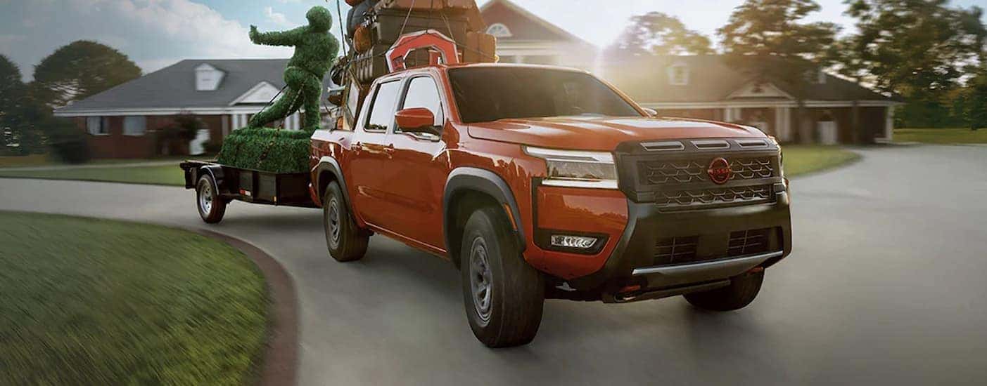 An orange 2026 Nissan Frontier towing a trailer.