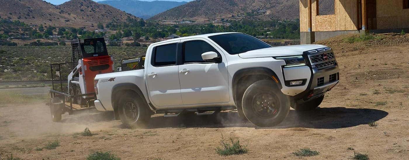 A white 2026 Nissan Frontier towing a trailer.