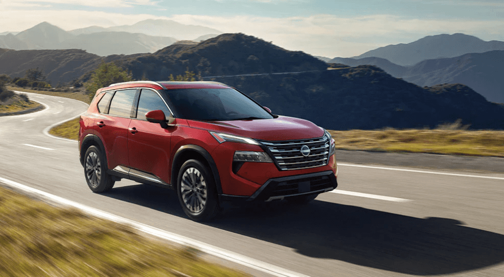 Red 2026 Nissan Rogue driving vs a 2026 Chevy Equinox