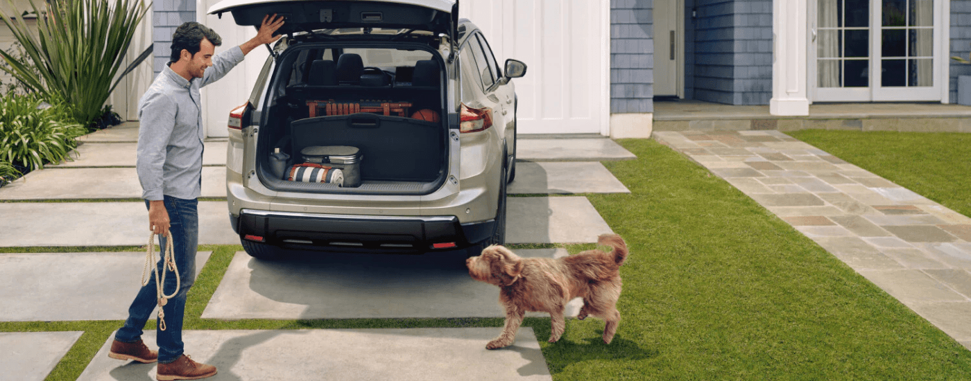 A person and a dog load the trunk of a 2026 Nissan Rogue