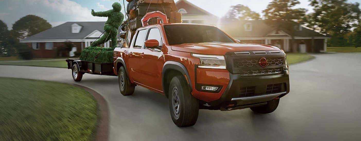 A red 2026 Nissan Frontier towing a trailer.