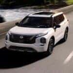 A white 2026 Nissan Rogue PHEV driving on a highway
