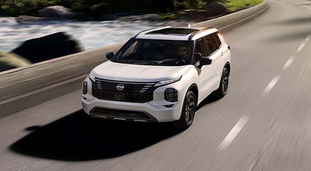 A white 2026 Nissan Rogue PHEV driving on a highway