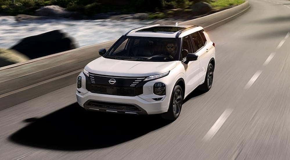 A white 2026 Nissan Rogue Plug-In Hybrid driving on a highway.