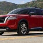 A red 2026 Nissan Pathfinder driving on a highway.